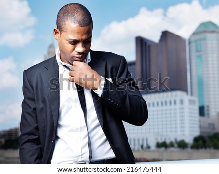 African man in suit thinking in front of city