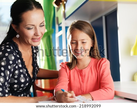 mother helping happy daughter with homework