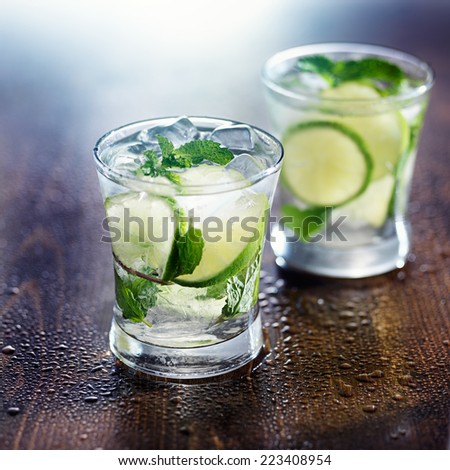 two mojito cocktails on wet wooden table