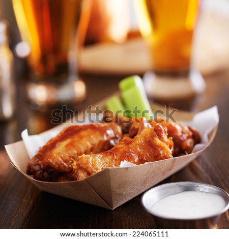 buffalo chicken wings in disposable tray with celery, ranch, and beer