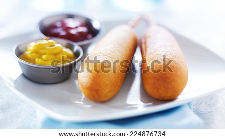 corn dogs on white plate with condiments panorama