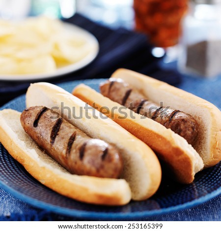 grilled bratwursts with potato chips and drink in the background