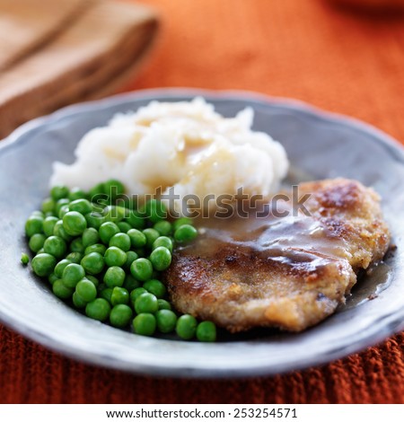 vegan meat alternative fried steak with peas and potatoes