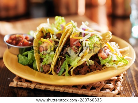 three beef mexican tacos with cheese and lettuce