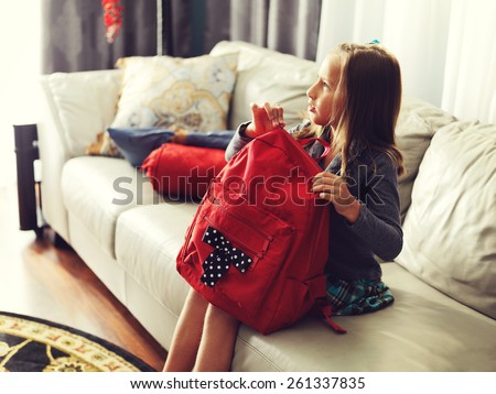 little girl ready for school at home with school bag.