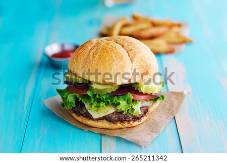 cheeseburger with fries and ketchup on rustic table top