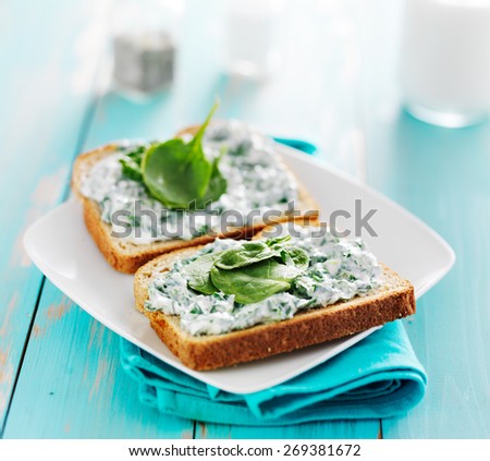toast with spinach cheese spread on it and leaf garnish