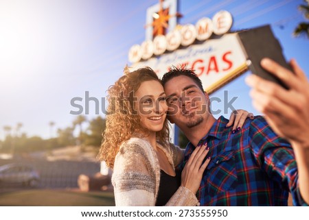 romantic couple taking selfie by welcome to las vegas sign with smart phone