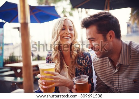 happy couple having a good time drinking beer together at outdoor pub or bar