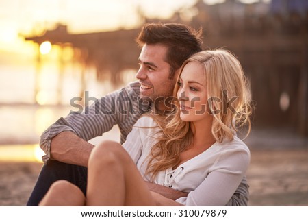 two lovers cuddling by santa monica pier during sunset