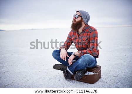 bearded hipster alone in the salt flats looking out in deep thought with copyspace composition