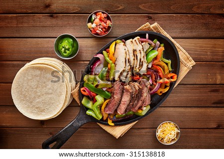 mexican steak and chicken fajitas in cast iron skillet shot top down with corn tortillas