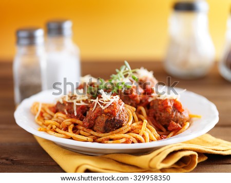 spaghetti and meatballs on rustic wooden table with yellow background