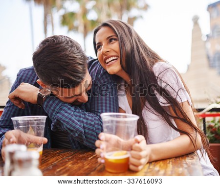 Hispanic couple laughing and having fun while drinking beer shot with selective focus