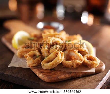 fried calamari rings on wooden tray with dipping sauce