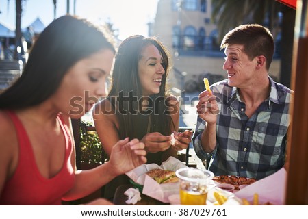 happy couple sharing french fry at outdoor restaurant