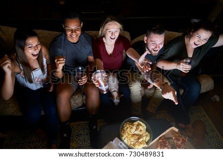 friends cheering while watching game on tv at night