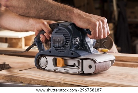 carpenter works with belt sander in carpentry