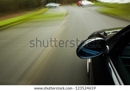 Side view of black car driving fast on the forest road