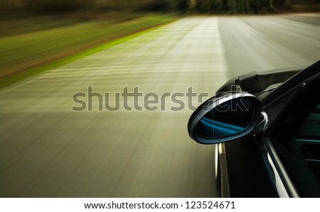 Side view of black car driving fast on the road