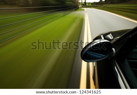 Side view of black car driving in forest road