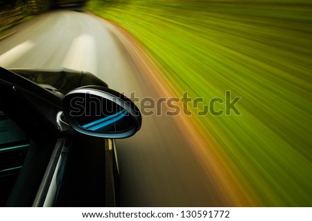Side view of black car driving on forest road.