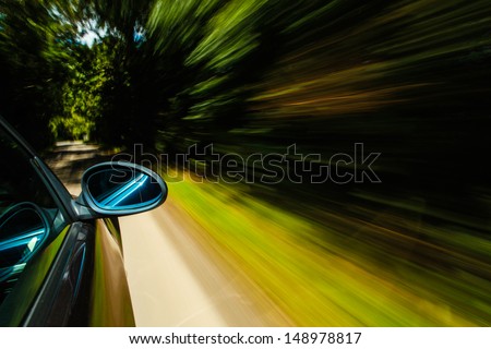 Mirror view of black car driving in forest.