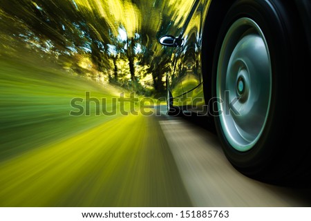 Rear side view of black car driving in forest.