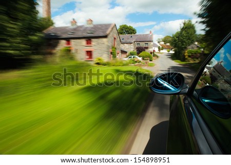 Side mirror view of car driving in the village.