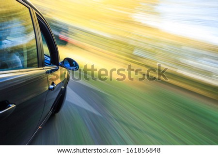 Side view of dark luxury car driving fast.