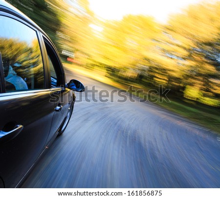 Side view of dark luxury car driving fast.