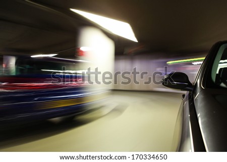 Mirror view of black car driving at underground car park.