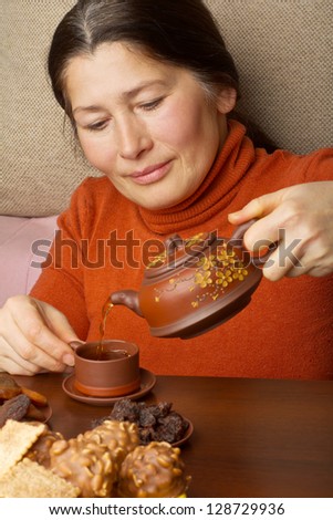 Asian woman pouring tea in cup