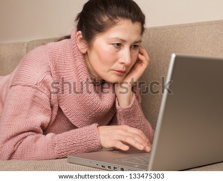Senior woman with  laptop, relaxing on the couch.