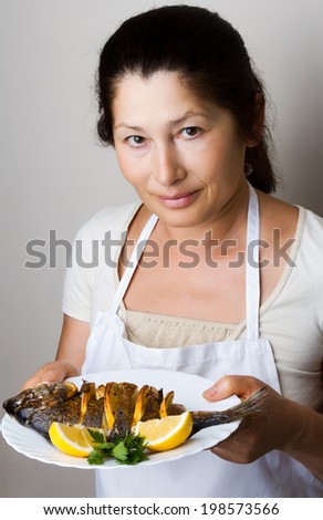 Female chef shows sea bream fish with lemon, parsley,garlic.