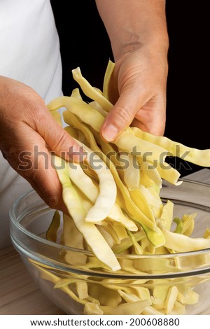 A pile of yellow string beans in a woman hands