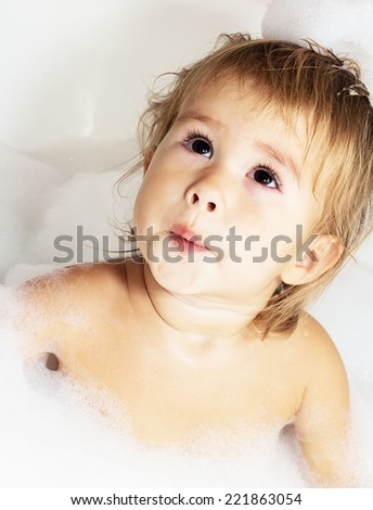Little girl surrounded soap suds.