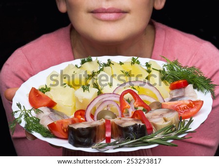 Woman chef offers a dish of smoked mackerel on the dish with vegetables