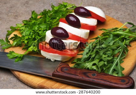 Mozzarella cheese with tomatoes and olives on wooden table