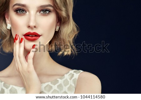 Beautiful model girl with short curly  hair and red lips . Red manicure on nails .Beauty and esthetic care
