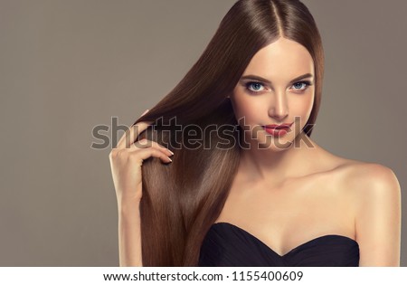 Beautiful model girl with shiny brown and straight long  hair . Keratin  straightening . Treatment, care and spa procedures. Smooth hairstyle. Care and beauty  products .