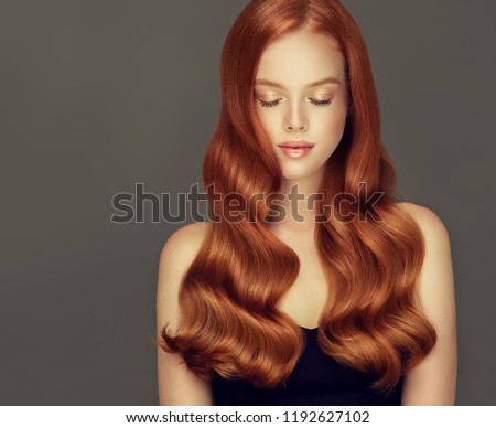 Young, red haired woman with voluminous hair.Beautiful model with long, dense, curly hairstyle .