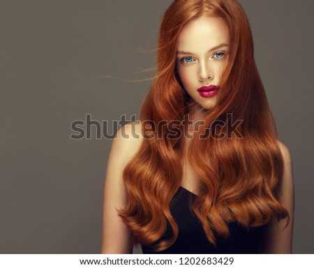 Young, red haired woman with voluminous hair.Beautiful model with long, dense, curly hairstyle .
