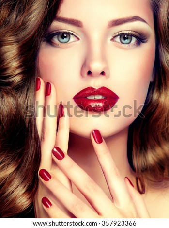 Beautiful model with curly hair and red manicure closeup . fashion trend image ,the girl with blue eyes , fashion makeup and red nails