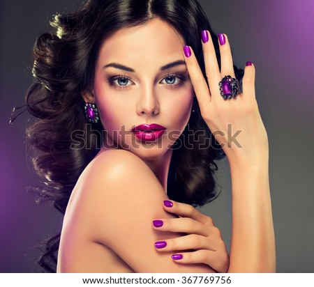 Model curly hair and jewelry , violet makeup , manicure on nails .  elegant hairstyle . Fashionable jewelry set , ring and earrings .