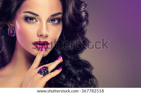 Model curly hair and jewelry , violet makeup , manicure on nails .  elegant hairstyle . Fashionable jewelry set , ring and earrings .