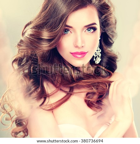 Beautiful model brunette with long curled hair and jewelry earrings