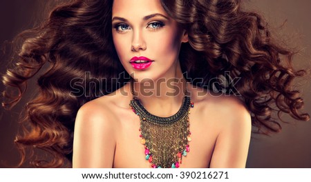 Beautiful model brunette with long curled hair and jewelry necklace .  Hairstyle small Curling