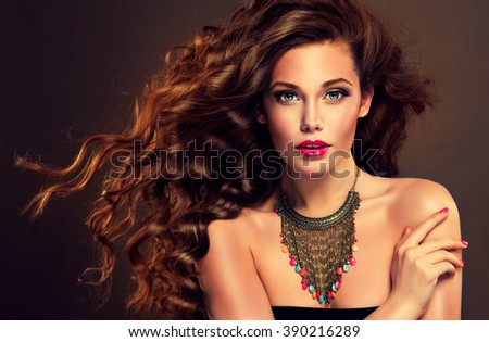 Beautiful model brunette with long curled hair and jewelry necklace .  Hairstyle small Curling