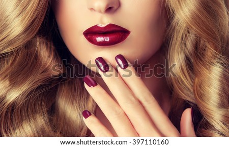 Beautiful girl with long wavy hair .  woman with red manicure .  girl with plum color nail Polish on the nails . Makeup and cosmetics